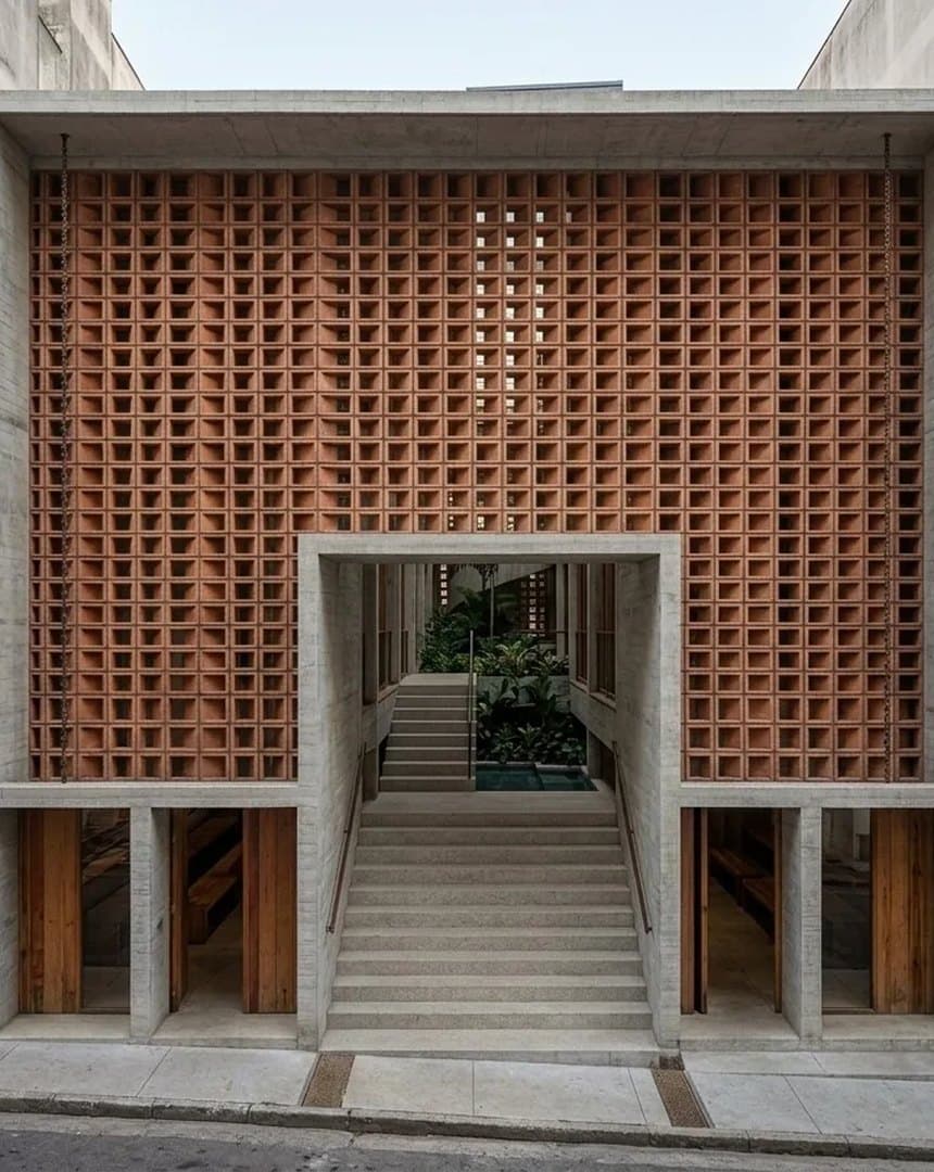 Perforated terracotta facade of the São Paulo infill, stair rising to a planted courtyard