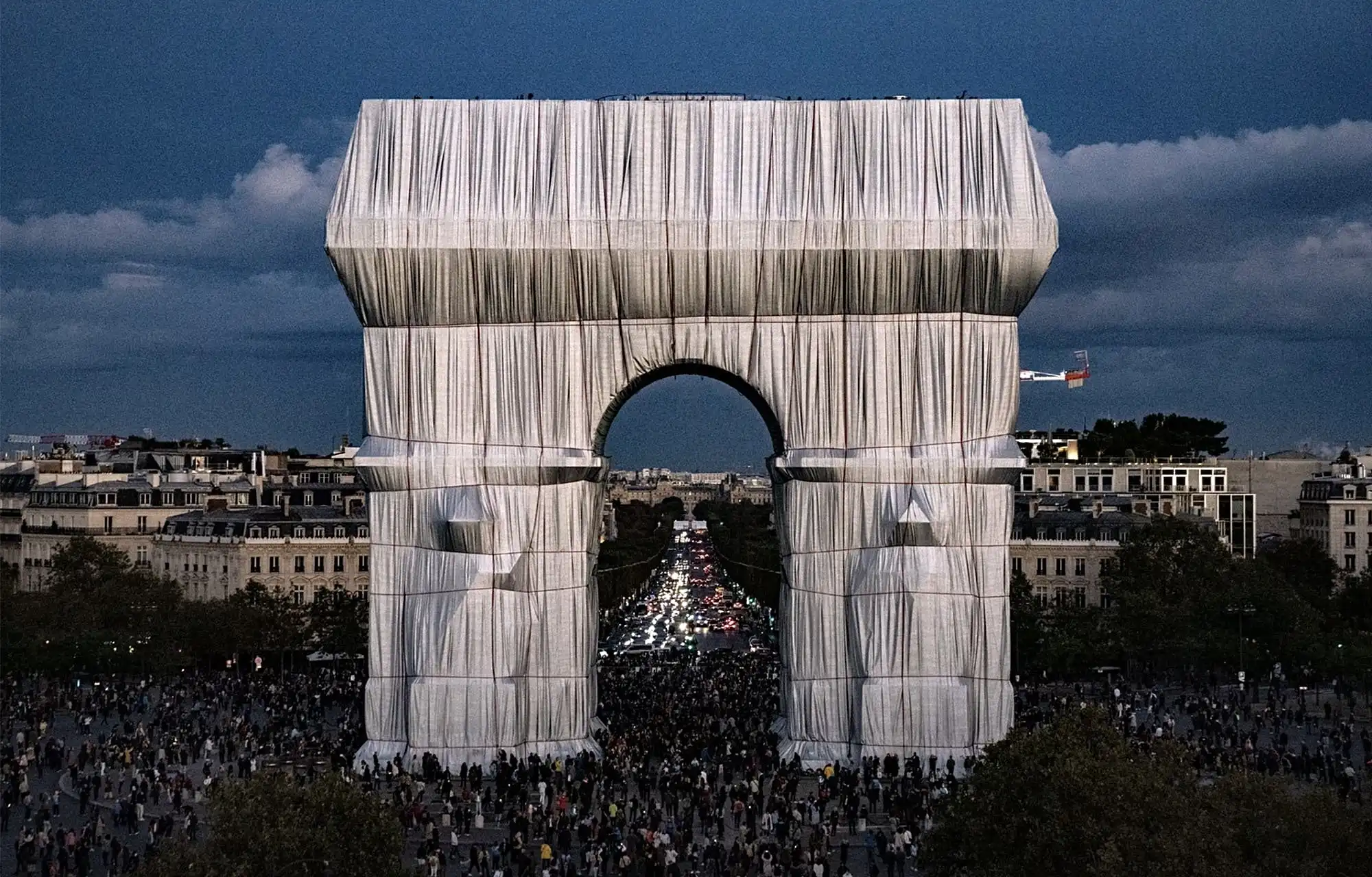 L'Arc de Triomphe, Wrapped. A temporary art installation where the Arc de Triomphe in Paris was enveloped in silvery-blue polypropylene fabric and red polypropylene rope.  Wolfgang Volz © 2021 Christo and Jeanne-Claude Foundation